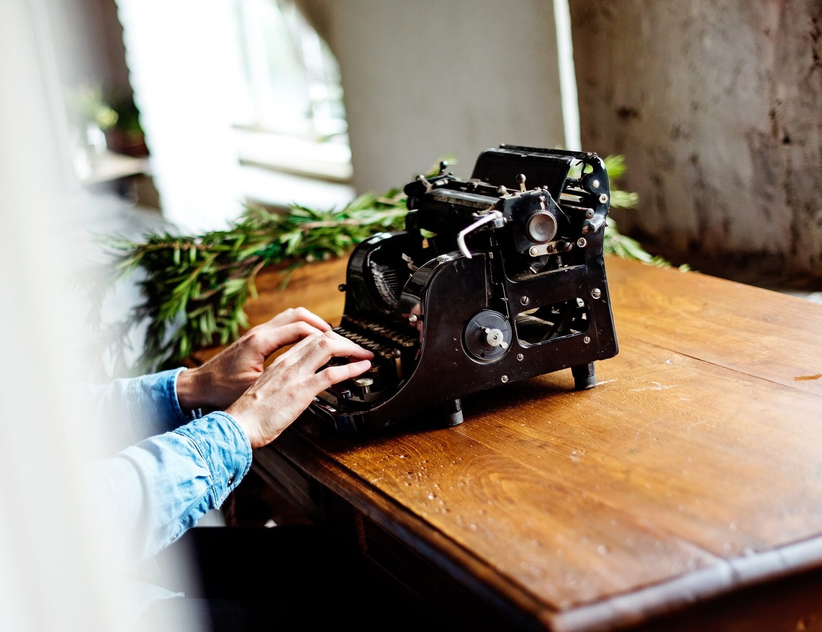 A hand at work on a mechanical typewriter — craft carried out by touch, not a screen.