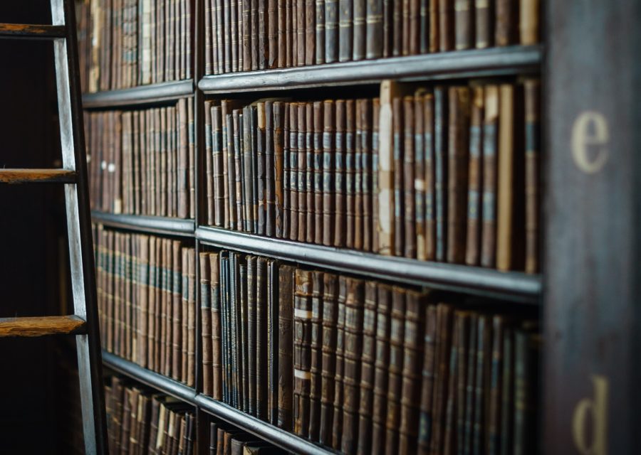 A library ladder against tall shelves of bound volumes.
