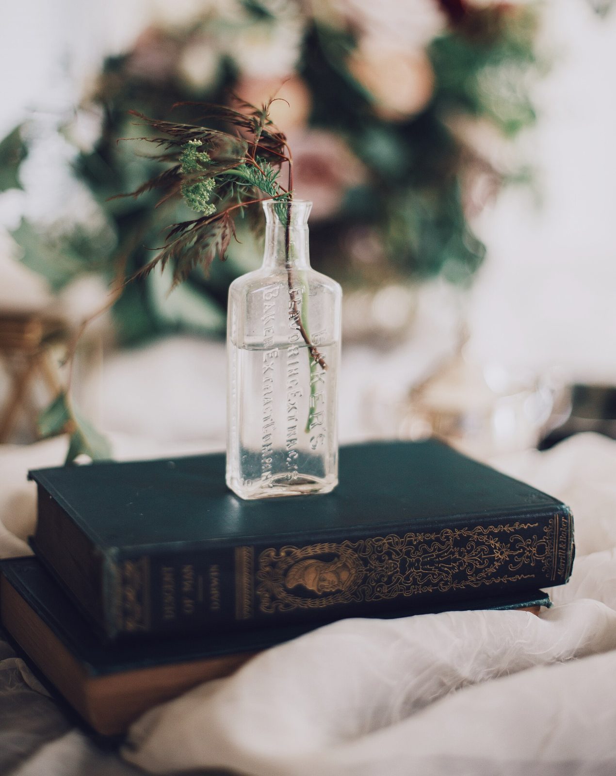 A glass bottle and an old book together on a marble surface.