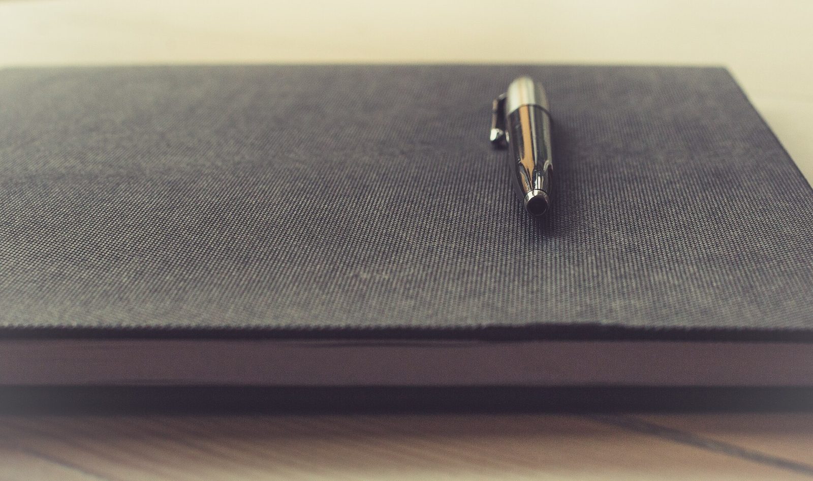 A pen clipped to the cover of a closed book.