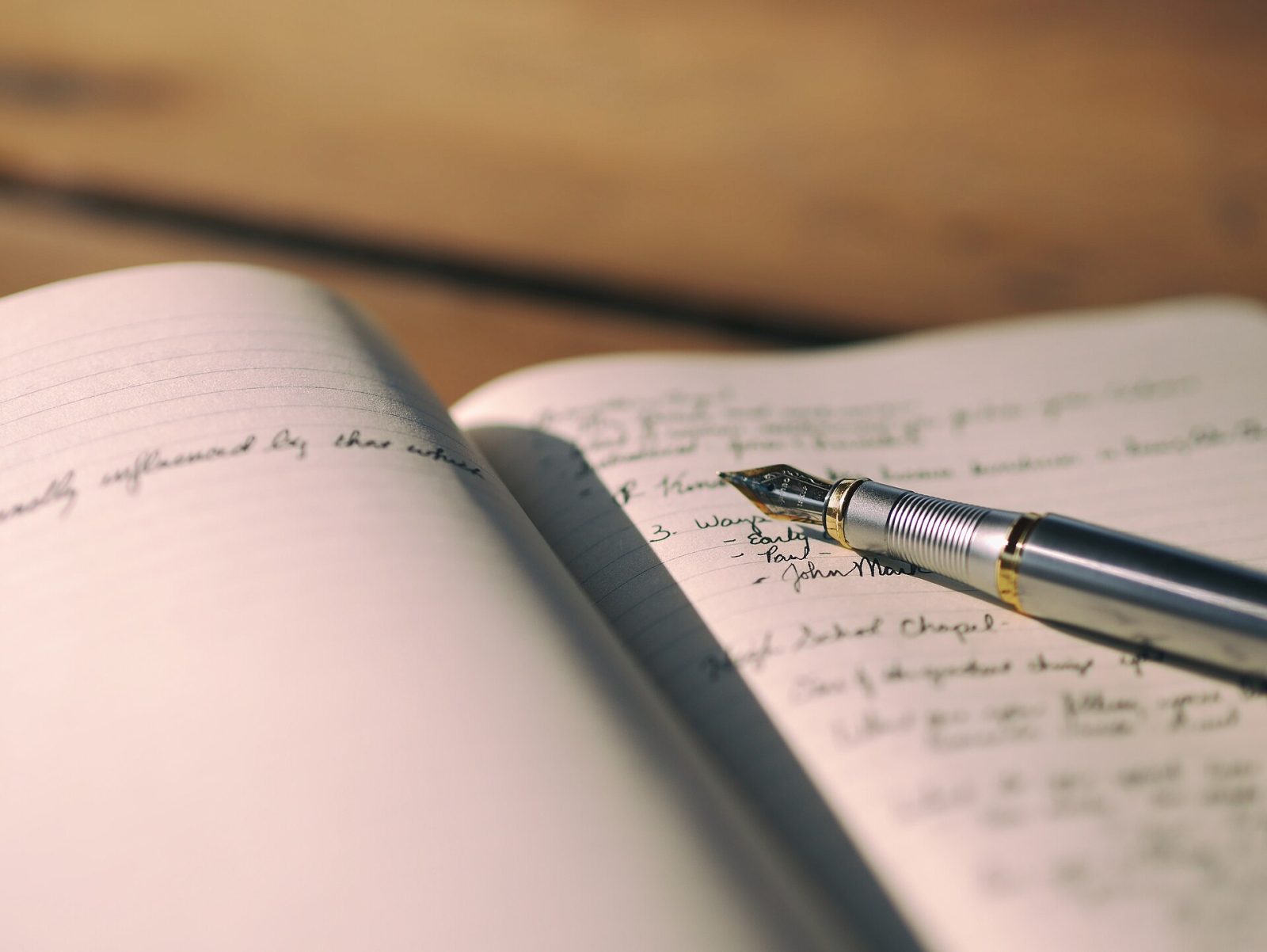 An open notebook mid-sentence, pen resting on the page.
